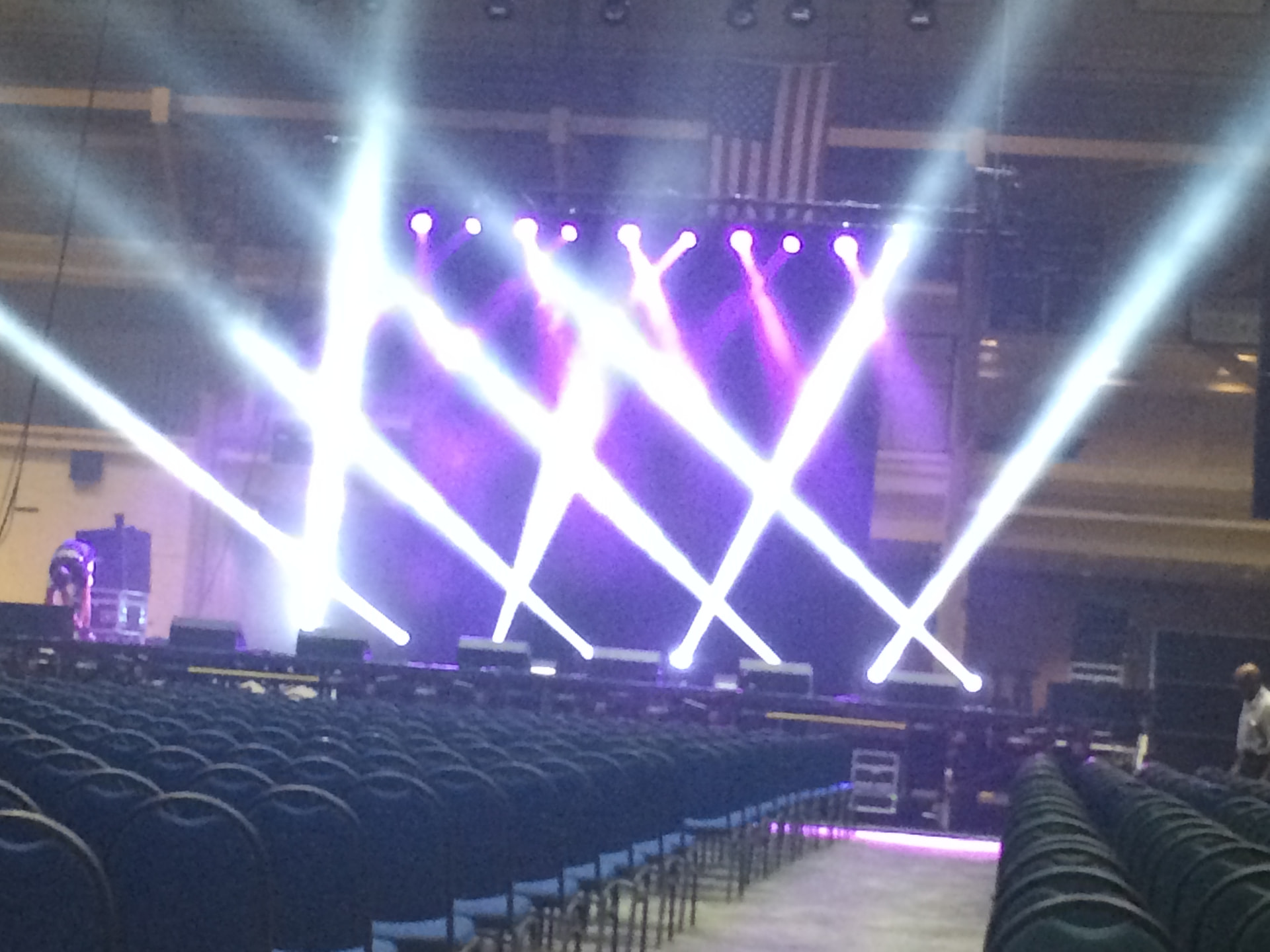 Arena stage with crossing white beam lights and purple wash before doors open